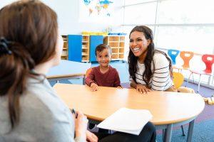 boy watches mom and teacher in meeting